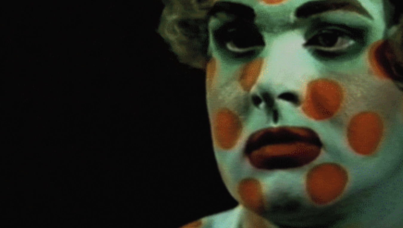A close up of Bowery's face painted with orange polka dots.