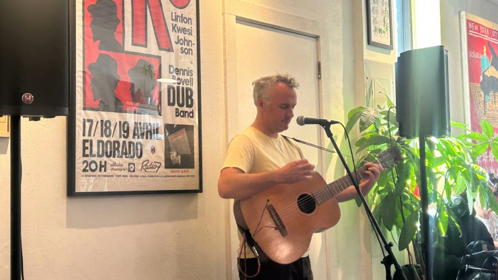 Photo of Phil Elverum playing acoustic guitar in a coffee shop
